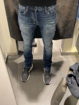 Jack&jones jeans - Säljer ett par blå slim fit jeans med slitningar och lätt tvättad look. Jeansen har klassisk femficksmodell, låg midja och dragkedjegylf. Perfekta för en avslappnad och trendig stil.