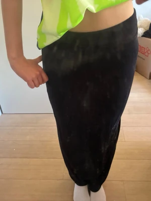Svart långkjol i enkel design - Säljer en svart långkjol med rak passform. Kjolen har en minimalistisk look utan synliga detaljer eller mönster och passar perfekt till en avslappnad eller stilren outfit. Materialet känns mjukt och följsamt mot kroppen.