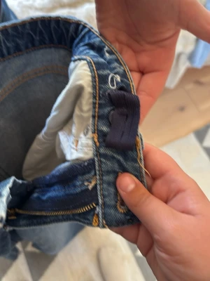Blå wide leg jeans från H&M - Säljer ett par blå wide leg jeans från H&M med hög midja och justerbar midja. Klassisk denimlook med synliga sömmar och dragkedja. Perfekta för dig som gillar avslappnad stil och vill ha bekväma jeans.