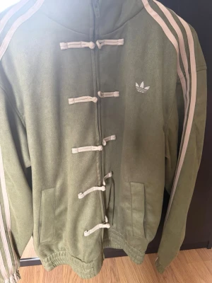 Adidas Original Tang jacka - Extremt ovanlig jacka från Adidas Originals som endast finns tillgänglig i Kina. Begränsad utgåva och mycket svår att få tag på i Sverige och övriga Europa. För dig som vill sticka ut med ett plagg som nästan ingen annan har. Köpte denna efter att ha varit i Shanghai i drygt 2 veckor. Finns även i andra färger och storlekar. Priset går att diskutera vid smidig affär eller vid köp av fler produkter. Jackan är i storlek M men passar även till storlek L.