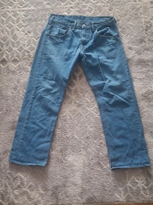 Blå raka jeans från Levi's - Klassiska blå jeans från Levi's med rak passform och fem fickor. Jeansen har normal midja och är tillverkade i slitstark denim. Perfekta för en avslappnad och tidlös stil.