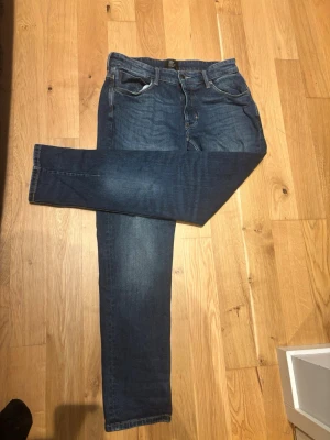 Neuw Jens 32-30 - Säljer ett par mörkblå slim fit jeans med klassisk femficksdesign och snygga slitningar framtill. Jeansen har normal midja och smal passform hela vägen ner. Perfekta till en avslappnad stil och passar till det mesta i garderoben.
