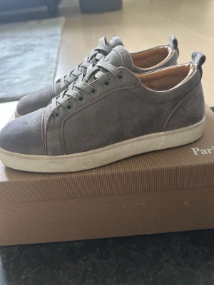 Gråa sneakers från Christian Louboutin - Stilrena gråa sneakers från Christian Louboutin i mocka med vita gummisulor och grå skosnören. Allt og tillkommer. Vid frågor och funderingar är det bara att skriva. Priset kan diskuteras vid en snabb affär