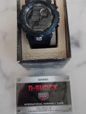 Casio G-Shock digital sportklocka 49mm - Casio G-Shock digital klocka med svart och silver design. Robust boett, digital display och vattentät upp till 20 bar. Klockan har flera funktioner som stegräknare och timer. Levereras med originalkartong och internationellt garantikort.