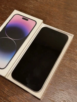 iPhone 14 Pro Max lila med trippelkamera - Säljer en iPhone 14 Pro Max i snygg lila färg. Telefonen har en stilren design med platt skärm, rundade hörn och baksida i glas. Utrustad med trippelkamera och Apple-logga på baksidan. Levereras i originalkartong. Batteriet 79% 256gb, priset kan diskuteras 