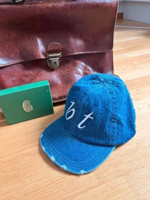 Blå denimkeps med broderi - Snygg blå keps från Bristol textiles svår att få tag i och kommer göra din stil 100% bättre. Skriv om du har några frågor 