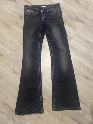 Svarta/mörkgråa bootcut jeans - Snygga svarta bootcut jeans,  med silvriga knappar på bakfickorna, jeansen är från Gina tricot och köptes för ca 250kr, jeansen är i bra skick och har andvänds några fåtal gånger. Priset kan diskuteras!