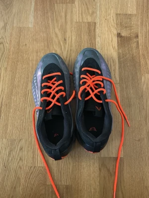 Anthony Edwards 1 size 40 men känns som 41 - Säljer ett par unika sneakers med svart mesh och syntetmaterial, coola grå-silver detaljer på sidorna och riktigt iögonfallande orangea skosnören. Snygg futuristisk design och låg profil som passar till streetwear och sportiga outfits.