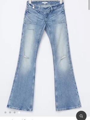 Ljusblå flare jeans med slitningar - Snygga ljusblå bootcut jeans med slitna detaljer på låren och knäna. Jeansen har en klassisk femficksmodell och utsvängda ben. Perfekta för en avslappnad och trendig look. Storlek S i 14+ på gina!
