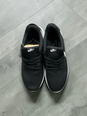 Nike Air svartvita sneakers - Svarta Nike Air sneakers med vit sula och vit swoosh-logga på sidan. Ovandelen är i meshmaterial för bra andningsförmåga och skon har klassisk snörning. Perfekta för en sportig och stilren look.