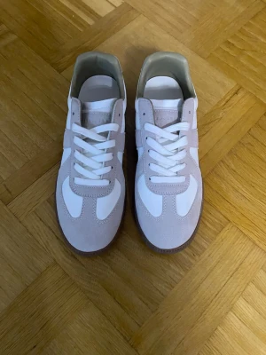 Maison Margiela Gats - Säljer ett par snygga sneakers med ljusgrå mockadetaljer, helt oanvända. Klassisk låg modell med stilren design som passar till allt. perfekt för sommaren nu. Behöver plats åt andra saker, kom med bud!