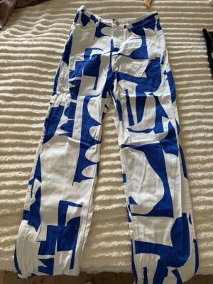Vita jeans med blått grafiskt mönster - Unika vita jeans från MONKI med ett stort blått grafiskt mönster. Raka ben och klassisk passform.