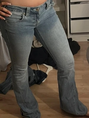 Bootcut jeans från True Religion - Säljer ett par ljusblå bootcut jeans från True Religion med klassiska kontrastsömmar och snygga fickdetaljer bak. Jeansen låg  midjade och är tillverkade i denim med lätt stretch för skön passform.