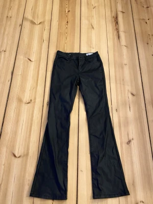 Svarta bootcut skin/läder byxor från Vero Moda - Snygga svarta byxor från Vero Moda med bootcut passform. Klassisk femficksmodell och medel midja. Perfekta för dig som är lång. 