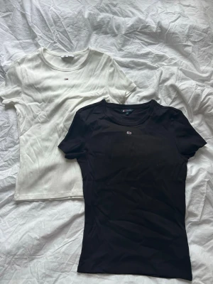 Tommy Hilfiger t-shirts svart & vit - Två klassiska t-shirts från Tommy Hilfiger, en i svart och en i vit. Båda har rund halsringning, korta ärmar och liten logga på bröstet. Perfekta basplagg i mjuk bomull som passar till allt.