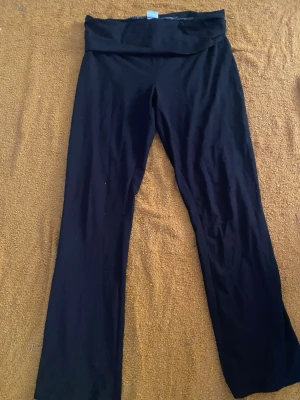 Svarta bootcut leggings - Svarta leggings med bootcut-ben och bred midjeresår. Mjukt och stretchigt material som sitter skönt. Perfekta för en avslappnad och trendig look.