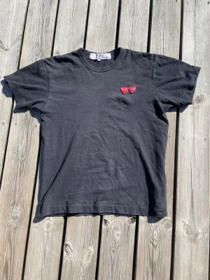 Comme des Garçons t-shirt  - Tjena säljer en snygg och unik Comme des Garçons t-shirt som är perfekt till sommaren. T-shirten är i storlek M men skulle säga att den passar S med då den är lite liten i storleken. Skicket är använt men utan fläckar och hål. Skriv om det finns några frågor eller funderingar🥂