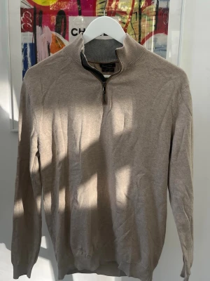Beige halvzip-tröja Massimo Dutti - Stilren beige tröja från Massimo Dutti med halv dragkedja och hög krage. Tillverkad i en mjuk mix av bomull, silke och kashmir. Ribbstickade muddar vid ärmslut och nederkant ger en snygg passform. Har ett hål i vänster armhåla enligt bild. 