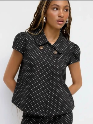 Svart prickig blus med krage - Svart blus med vita små prickar, helt ny med lapp och allt den är i xl men jag skulle säga att den känns som en medium - larg den skulle även funka jätte bra som en liten kofta
