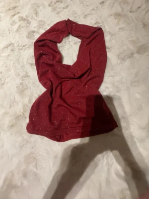 Glittrig vinröd croppad topp XS - Säljer en vinröd croppad topp i storlek XS med glittrigt tyg och snygg draperad urringning. Toppen är ärmlös och har en figurnära passform som framhäver midjan. Perfekt för dig som vill sticka ut lite extra!