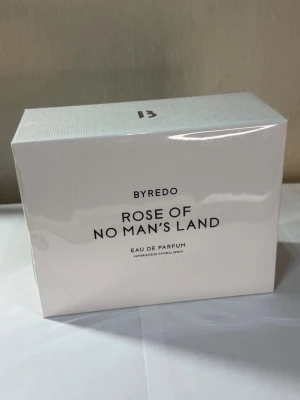 Byredo Rose of No Man's Land parfym - Byredo Rose of No Man's Land Eau de Parfum i en stilren vit kartong med svart text. Parfymen är känd för sin fräscha och blommiga doft med ros som huvudnot. Förpackningen är elegant och minimalistisk, perfekt för dig som gillar exklusiva dofter.