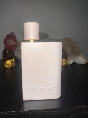 Burberry Her parfym ljusrosa flaska - Burberry Her parfym i en stilren, ljusrosa flaska med rundade kanter och guldiga detaljer vid halsen. Rymmer 50ml, använd ca 5 gånger. Så mycket mer än hälften kvar. 