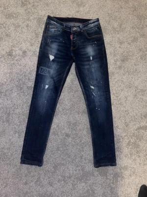 Mörkblå skinny jeans från Dsquared2 - Snygga mörkblå skinny jeans från Dsquared2 med slitningar och distressed detaljer. Jeansen har klassisk femficksdesign, låg midja och en patch med logga på baksidan. Perfekta för en trendig streetstyle-look. Fraktar direkt pris kan alltid diskuteras storlek är xs/s