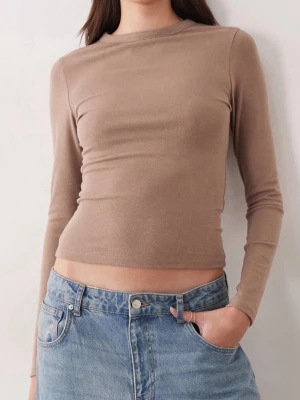 Beige långärmad croppad topp - Trendig beige långärmad topp med croppad passform och rund halsringning. 