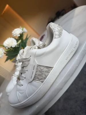 Vita Michael Kors sneakers - Snygga vita sneakers från Michael kors. Fåtal gånger använda men lite slitningar på framsidan av ena skon, se bild! 