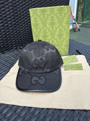 Svart keps från Gucci med GG-mönster - Pris kan diskuteras. Snygg svart keps från Gucci med det klassiska GG-mönstret över hela kepsen. Kepsen har böjd skärm och är tillverkad i ett slitstarkt tyg med detaljer i svart. Perfekt accessoar för dig som vill ha en exklusiv och trendig look.