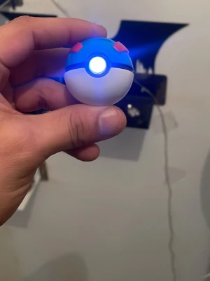 Mini Great Ball Pokémon LED-lampa - Cool Mini Great Ball LED-lampa från Pokémon. Lampan är rund, blå och vit med röda detaljer och har en lysande LED i mitten. Perfekt som dekoration eller nattlampa för Pokémon-fans. Kommer med en svart bas med Pokémon-logga. Box och manueler medföljer. 
