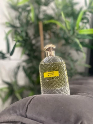 Stronger With You parfymflaska 100ml - Snygg parfymflaska med guldfärgat lock och rutmönstrad glasdesign. Flaskan har en gul etikett med texten 'Stronger With You' och innehåller en ljusgul vätska. Perfekt för dig som gillar stilrena och eleganta detaljer på parfymhyllan.