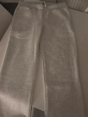 Grå mjukisbyxor i rak modell - Mysiga grå mjukisbyxor i rak passform med resår i midjan. Tillverkade i ett mjukt och bekvämt material som passar perfekt för chill dagar hemma. Klassisk stil utan synliga loggor eller detaljer.