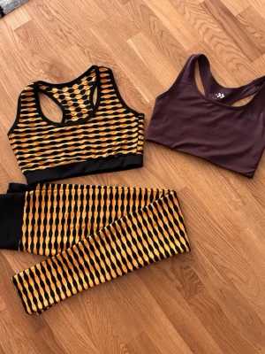 Snyggt sportset (leggings + sport-bh)  - Snyggt sportset (leggings + sport-bh) i svart/guld med unik design ✨ Ingår även en brun topp från märket Lager 157 🤎 Alla plagg är i storlek S – perfekta för träning eller vardag. Skick: Mycket fint skick, nästan som nya – inga fel 💯 Varför köpa? ✔ Bekvämt och stretchigt material ✔ Trendig och snygg look ✔ Perfekt för gym eller casual ✔ Riktigt bra deal för priset