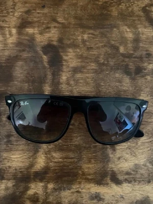 Svarta Ray-Ban Boyfriend solglasögon - Klassiska svarta Ray-Ban Boyfriends solglasögon. Snygg och tidlös design med svarta bågar och mörka glas. Perfekta för att lyfta din stil med en ikonisk look.