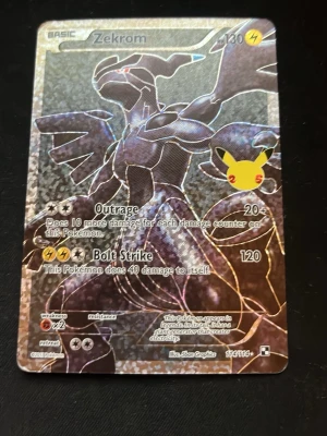 Pokémonkort Zekrom 25th Anniversary - Säljer ett holografiskt Pokémonkort med Zekrom från 25th Anniversary-serien. Kortet har en glittrig yta, el-typ och Pikachu-logga. Perfekt för samlare eller Pokémonfans som vill utöka sin samling.