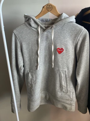 Grå hoodie från Comme des Garçons Play - Snygg grå hoodie från Comme des Garçons Play som passar perfekt inför sommaren! Hoodien är i storlek S och är i bra skick. Hör av dig vid frågor eller funderingar/ fler bilder! Priset kan självklar diskuteras också☺️