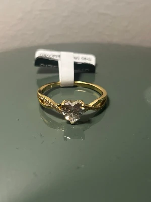 Guldfärgad ring med hjärtformad sten - Jättefin gult guld platerad silver ring från Jeulia🤍  Säljer denna då den tyvärr är för liten för mig och öppet köp har gått ut. Men ringen är i helt nyskick med alla lappar och tillhörigheter kvar. Medföljer en liten påse samt ett giftcard ifall man vill ge bort den💞 Material: sterling 925 silver  Nypris: 1 500kr På hemsidan just nu: 1 100kr Köp gärna av mig istället för hemsidan då det känns väldigt tråkigt att inte själv kunna använda  den💞🥹kan absolut tänka mig diskutera pris💞 Storlek 7,5US
