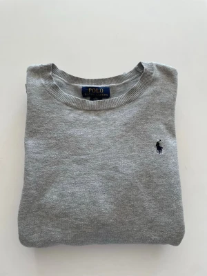 Grå tröja från Polo Ralph Lauren - En snygg grå stickad Ralph lauren tröja i bra skick. Tröjan är i storlek XL men sitter som en S/M.            