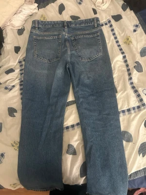 Blå raka jeans med rå kant Zara - Säljer ett par klassiska blå jeans med rak passform och rå, avklippt kant nertill. Jeansen har fem fickor och normalhög midja. Perfekta för en avslappnad och trendig look. Materialet är denim i bomull.