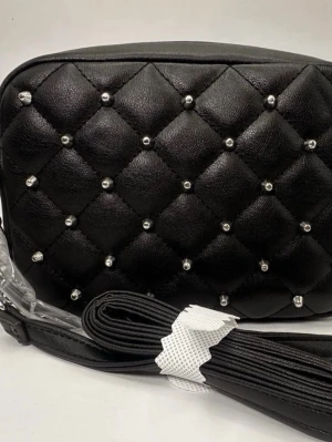 Rebecca Minkoff Svart quiltad handväska med nitar - Snygg svart handväska i quiltat konstläder med silverfärgade nitar och kedjedetaljer på handtaget. Väskan har en avlång form och dragkedja upptill. Perfekt accessoar för dig som gillar en edgy och trendig look.