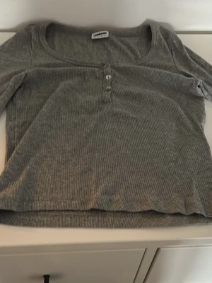 Grå ribbad långärmad topp noisy may  - Grå långärmad topp från noisy may  i ribbad bomullsmix. Modellen har rundad urringning och tre knappar framtill. (Köpare står för frakten💕)