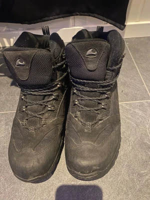 Svarta kängor från Viking - Svarta kängor från Viking med högt skaft och snörning. Tillverkade i slitstarkt material med foder av 90% polyester och 10% ull för extra värme. Perfekta för kalla dagar och outdoor-äventyr. Klassisk design med robust sula och detaljer i mesh.