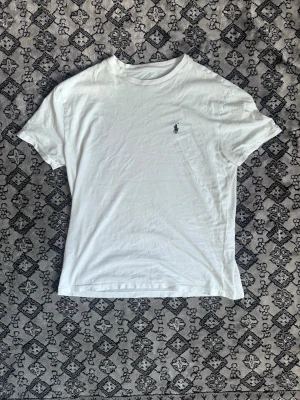 Vit t-shirt från Ralph Lauren - Klassisk vit t-shirt från Ralph Lauren med liten broderad logga på bröstet. T-shirten har rund halsringning och korta ärmar. Perfekt basplagg som funkar till allt och är tillverkad i mjuk bomull för skön känsla.
