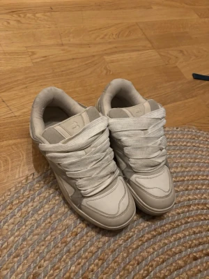 Vita och beige sneakers från Bershka  - Säljer ett par chunky sneakers från Bershka i vitt och ljusgrått. Skorna har breda vita snören, rund tå och en tjock sula. Ovandelen är i en mix av mocka och syntetmaterial med snygga detaljer på sidorna och logga på plösen.
