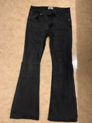 Svarta bootcut jeans - Säljer ett par svarta bootcut jeans med klassisk femficksmodell och utsvängda ben. Jeansen har normal midja och är tillverkade i ett mjukt denimtyg. Perfekta för dig som gillar retrostil och vill ha ett par bekväma jeans med snygg passform.