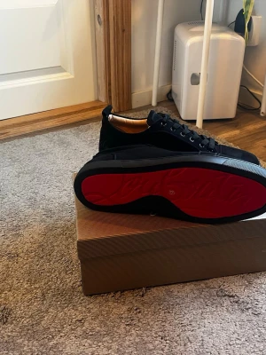 Svarta Louboutin sneakers med röd sula - Snygga svarta sneakers från Christian Louboutin med klassisk röd sula. Blev lite ändrade planer då dom inte passade sonen. Storlek 45 prutat och klart. (A kopior)