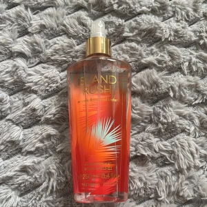 Island Rush body mist Victoria's Secret - Island Rush är en body mist från Victoria's Secret med tropisk känsla. Flaskan är genomskinlig med orange och guld detaljer samt ett palmbladsmotiv. Spraylocket är guldigt och flaskan rymmer 250 ml. Perfekt för dig som gillar fräscha och exotiska dofter.