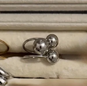 Silverfärgad ring  - Trendig ring i silverfärgad  med tre stora, blanka pärlor som dekoration. Ringen har en öppen design och en modern, minimalistisk look som sticker ut. Perfekt accessoar för dig som gillar statement-smycken.