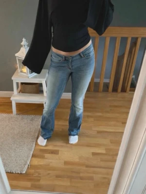 Blå bootcut jeans - Säljer ett par ljusblå bootcut jeans med låg midja. Jeansen är tillverkade i denim med lätt stretch. Perfekta för en avslappnad och trendig look. Har sprettat upp byxorna då jag tyckte dom var för korta på mig som är 170